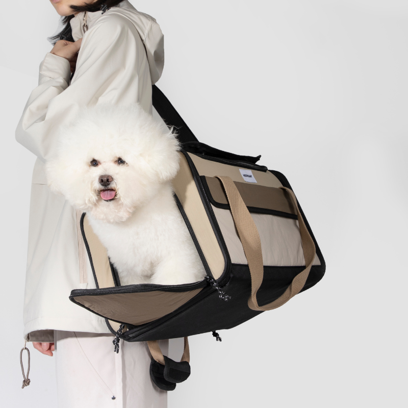 White dog in beige foldable pet carrier carried over shoulder