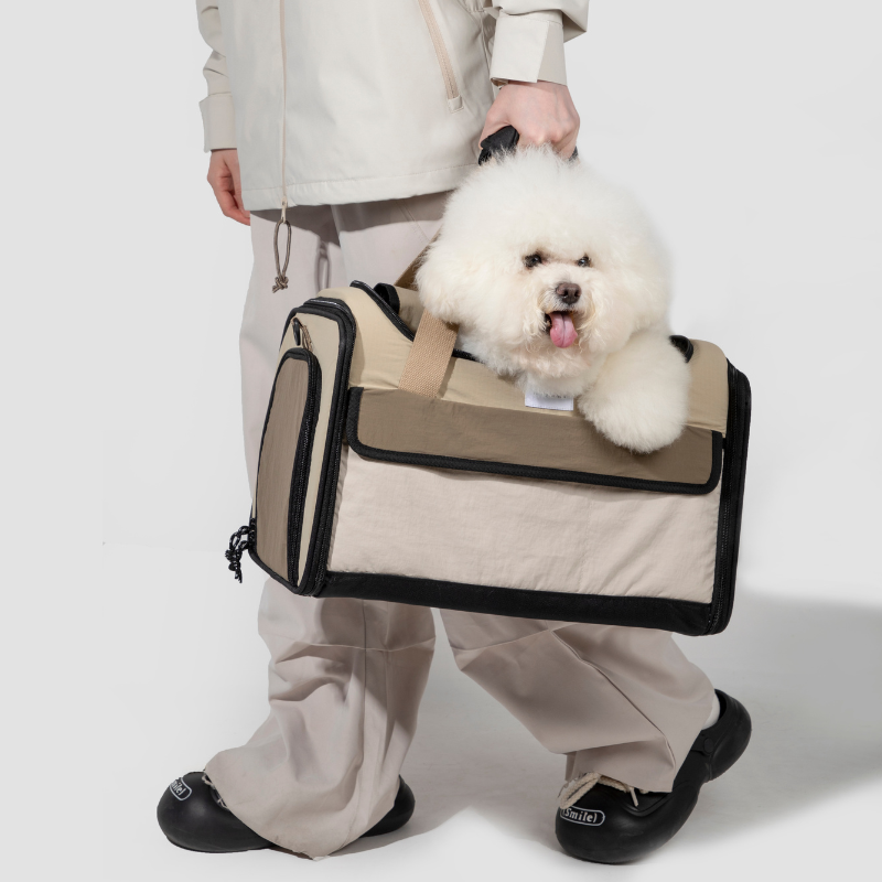 White dog riding in beige airline approved foldable pet carrier by owner