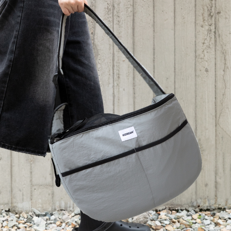 Close-up of gray outdoor pet tote shoulder bag carried by owner