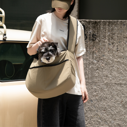 Owner wearing olive outdoor pet tote shoulder bag with small dog inside