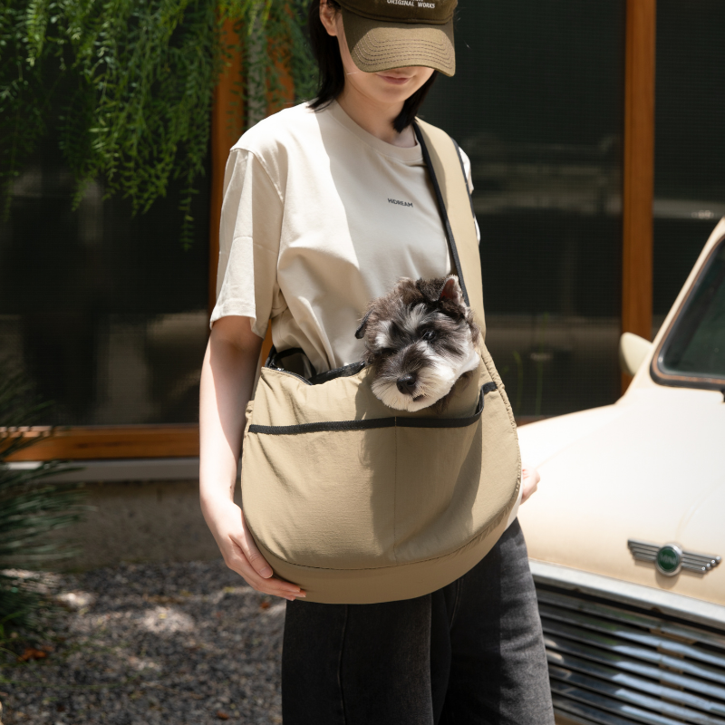 Owner carrying olive outdoor pet tote shoulder bag with small dog