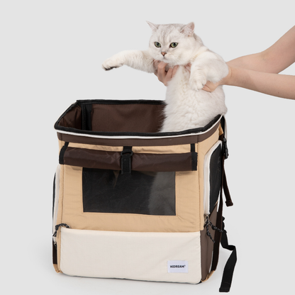 Beiger Haustier-Rucksackträger, bei dem eine weiße Katze durch die obere Öffnung eingesetzt wird