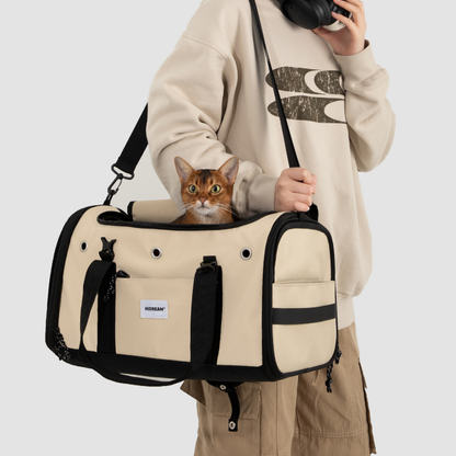 Beiger toast-farbener Fluggast-Haustiertransporter vom Besitzer getragen, mit orangefarbener Katze darin