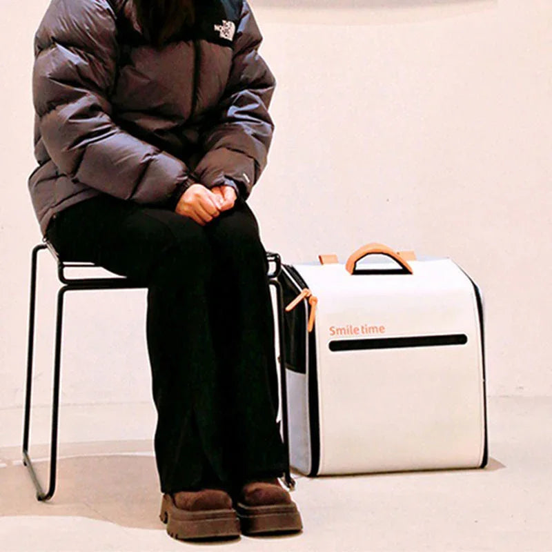 Weißer Smiletime Katzentragerucksack neben einer sitzenden Person platziert