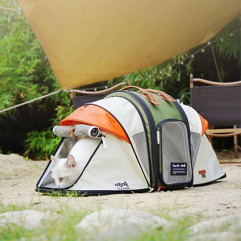 Orangefarbene und grüne zeltförmige Katzen-Rucksack-Tragetasche in der Nähe eines Campingplatzes