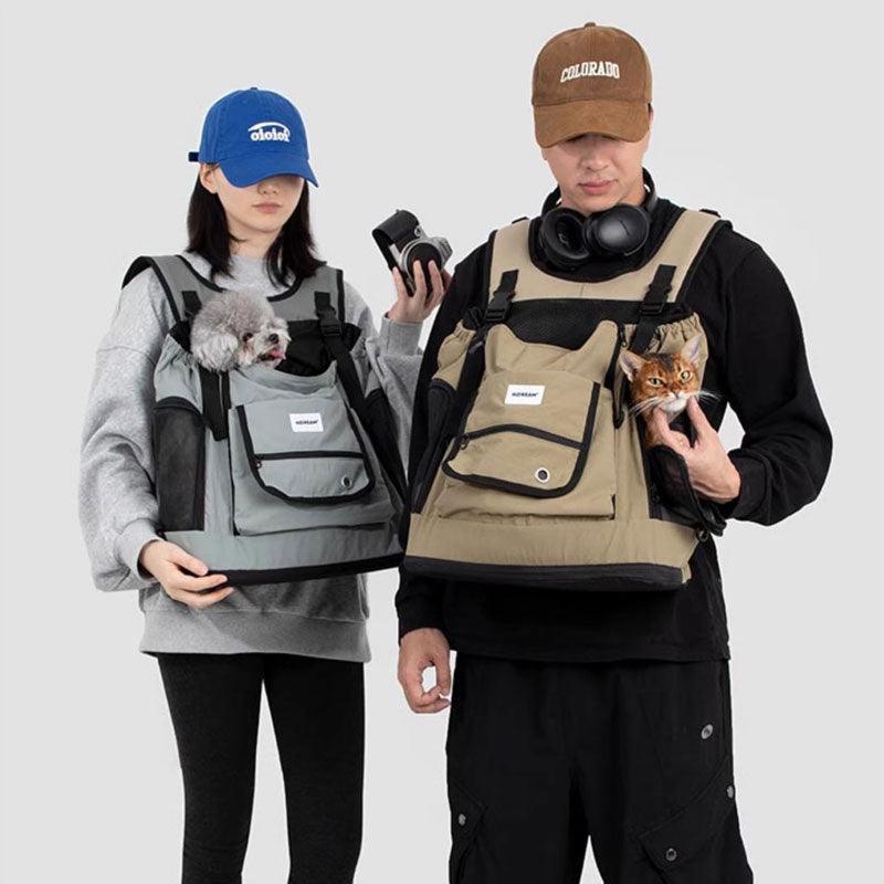 Zwei Personen tragen graue und beige Brustträger-Rucksacks mit Haustieren darin
