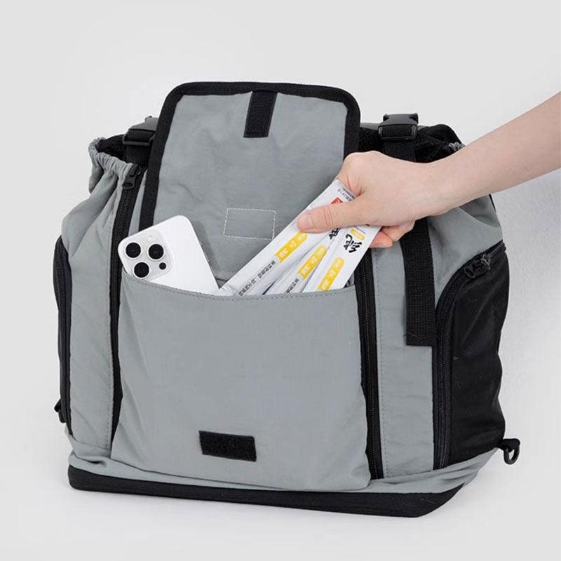 Hand legt Gegenstände in die hintere Tasche des grauen Träger-Rucksacks