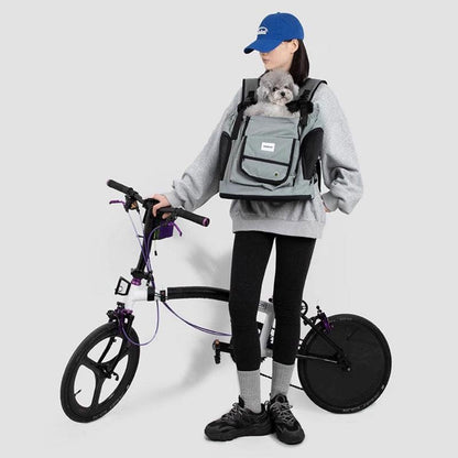 Person steht mit grauem Brustträger-Rucksack und Fahrrad
