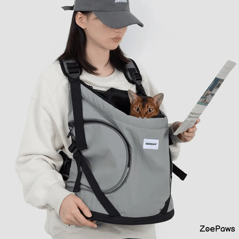 Woman wearing gray HiDREAM front pet carrier with Abyssinian cat peeking out while reading newspaper