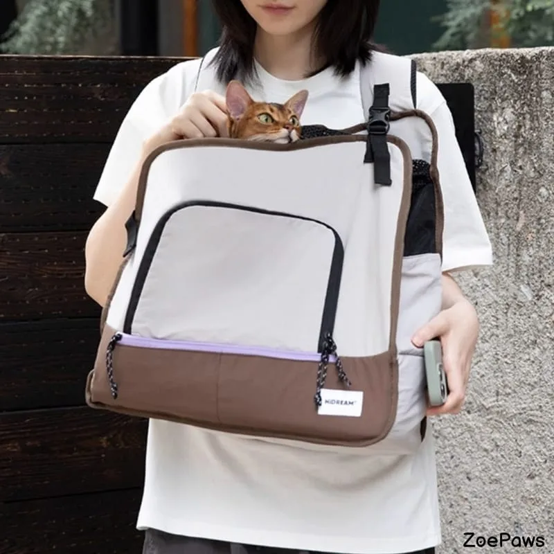 Orange tabby cat peeking out of HiDREAM pet carrier backpack held by person in white shirt