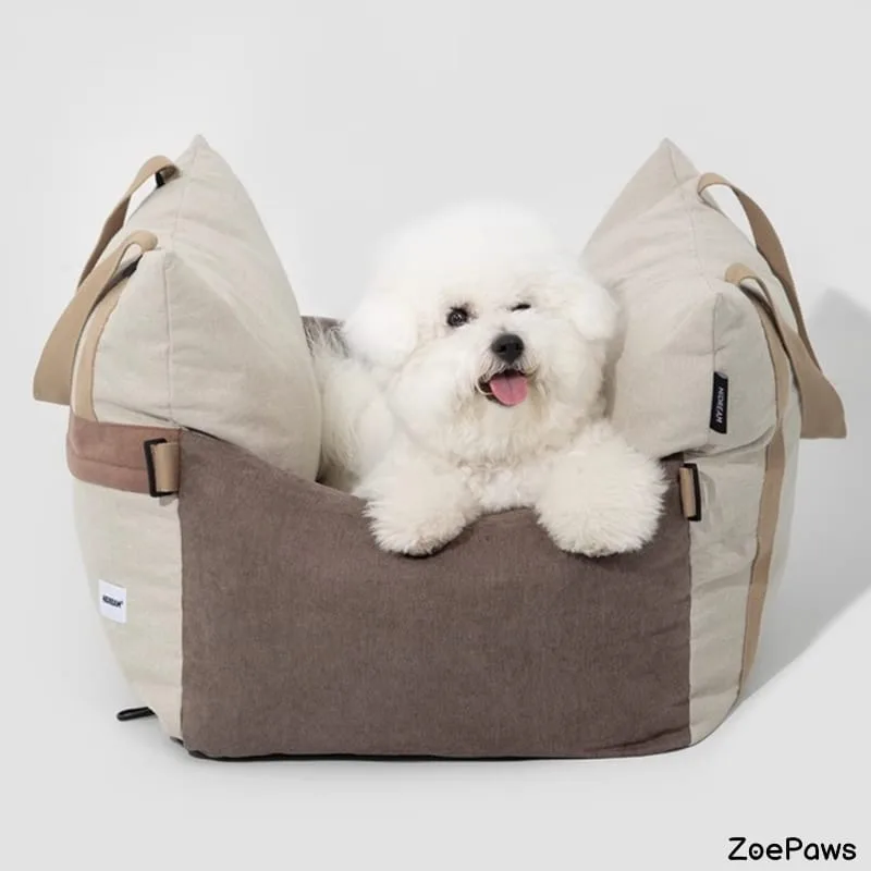 Fluffy white Bichon Frise dog sitting in a brown and beige ZoePaws pet car seat bed